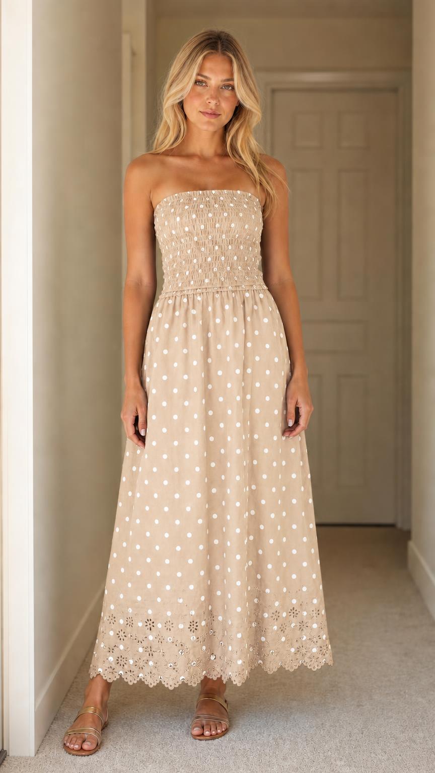 Front view of woman wearing beige polka dot strapless maxi dress