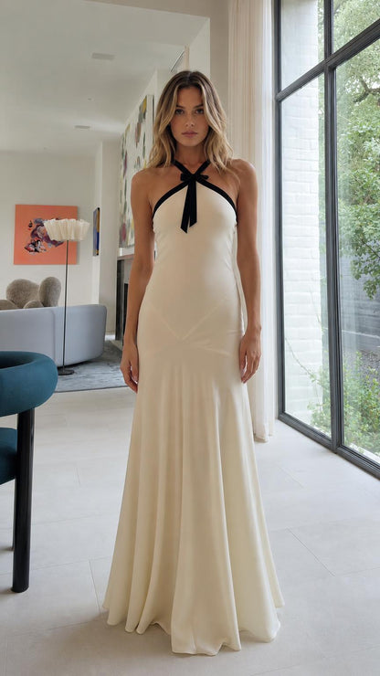 Front view of Ivory halter neck maxi dress with black bow