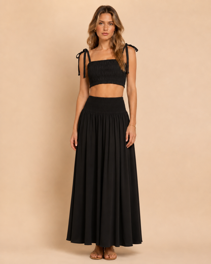 Front view of black smocked tie-shoulder crop top and matching maxi skirt set