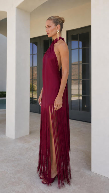 Model wearing burgundy satin halter fringe maxi dress side view