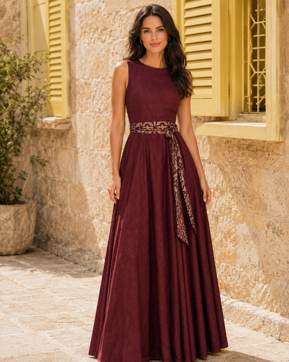 Front view of burgundy sleeveless shimmer maxi dress with patterned waist sash