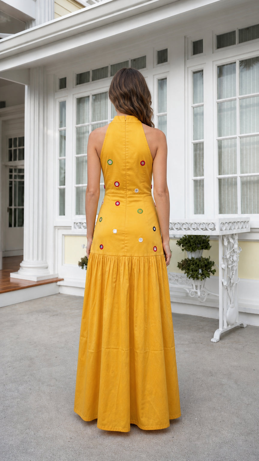 Back view of woman wearing yellow high-neck embellished maxi dress