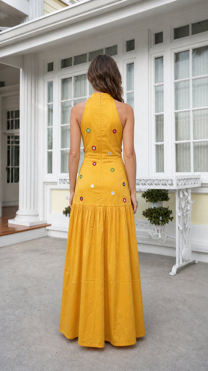 Back view of woman wearing yellow high-neck embellished maxi dress