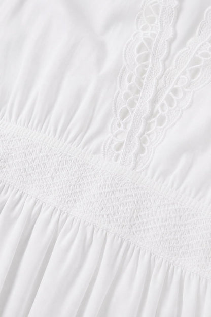 Close-up detail of white fabric, smocked waist, and lace trim