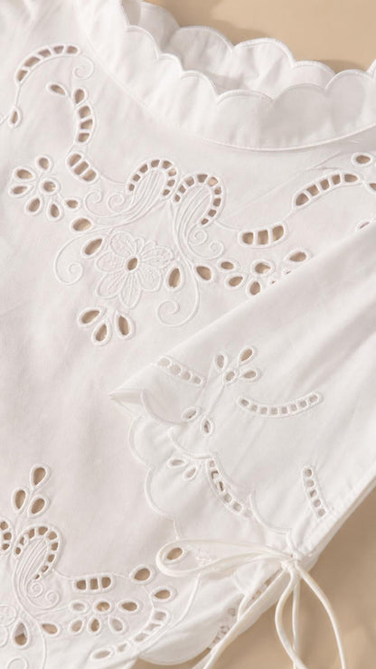 Close-up detail of white eyelet embroidery and scalloped hem
