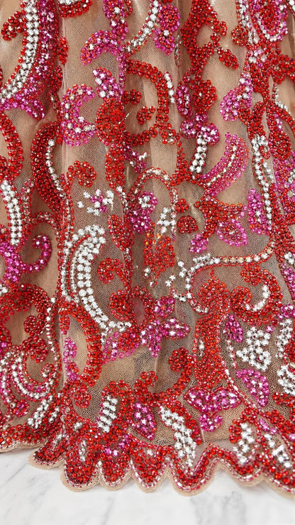 Close up of intricate red and pink beadwork on mesh