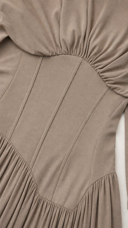 Close-up detail of structured corset waist and pleated fabric on taupe dress