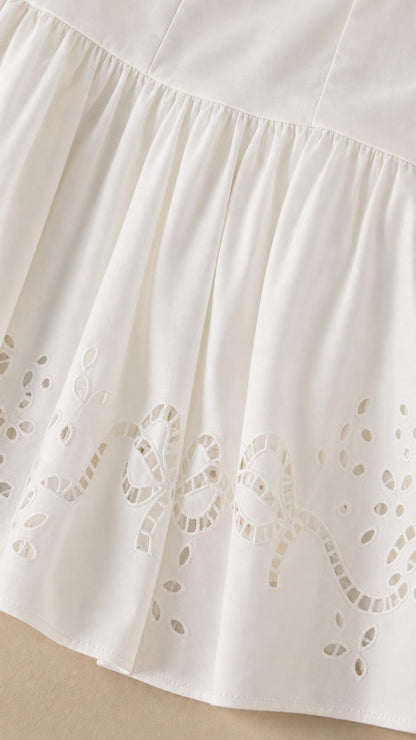 Close-up of embroidered cutwork hem on white mini dress