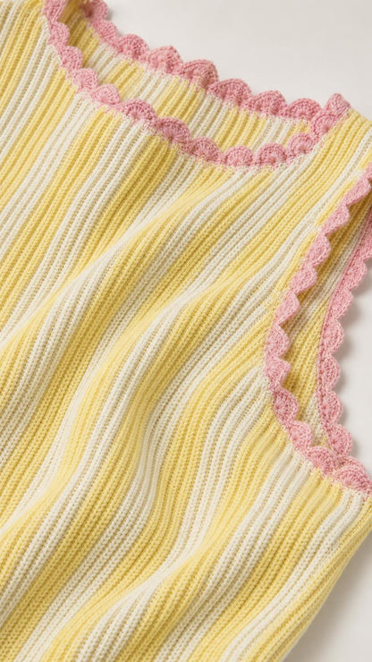 Close-up detail of yellow knit fabric and scalloped pink trim