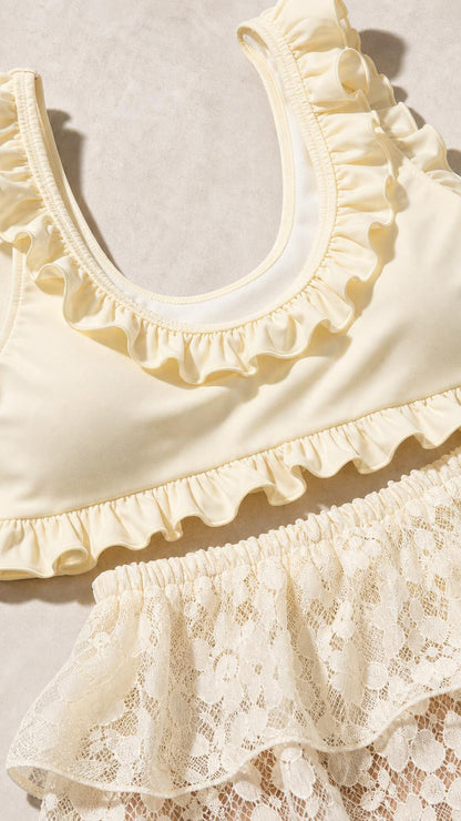 Close-up detail of ivory ruffled neckline and lace waistband