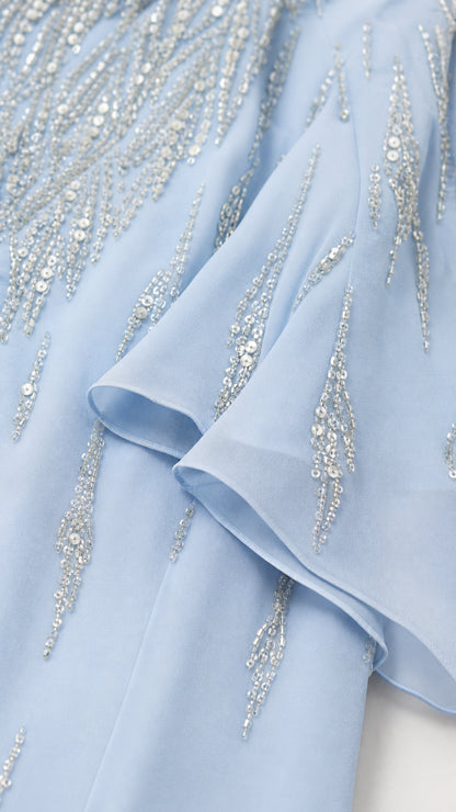 Close-up detail of light blue fabric beadwork and ruffles