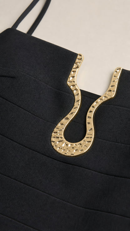 Close-up of gold neckline hardware detail on black dress