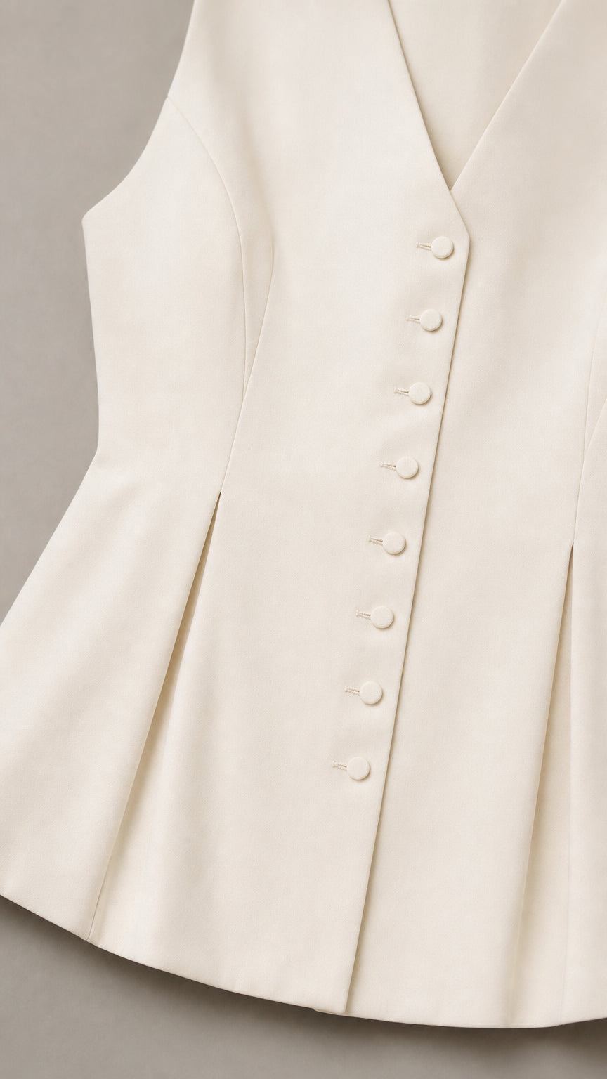 Close up of white vest button details and peplum hem