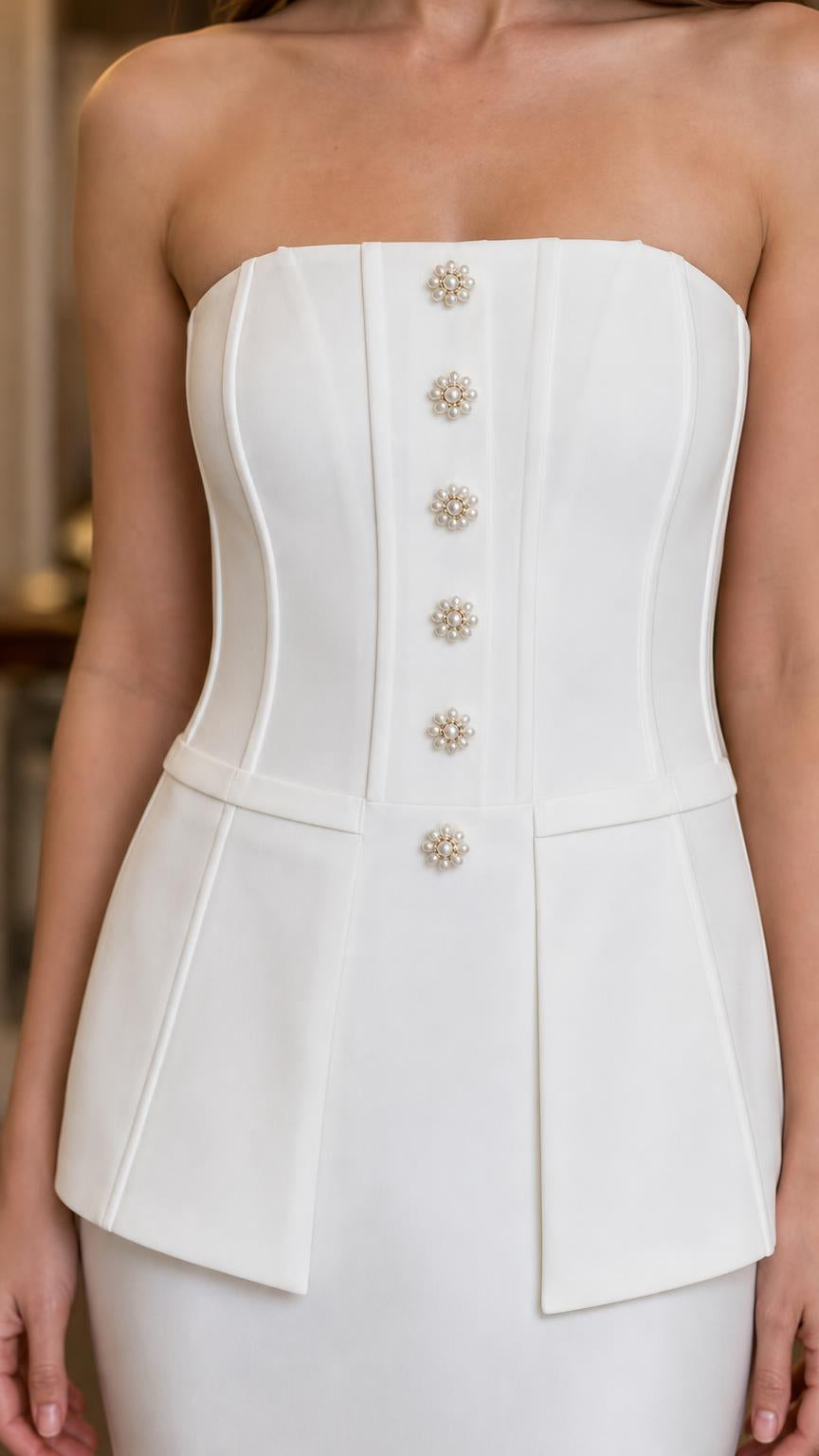 Close-up detail of structured corset bodice and crystal button accents on white dress