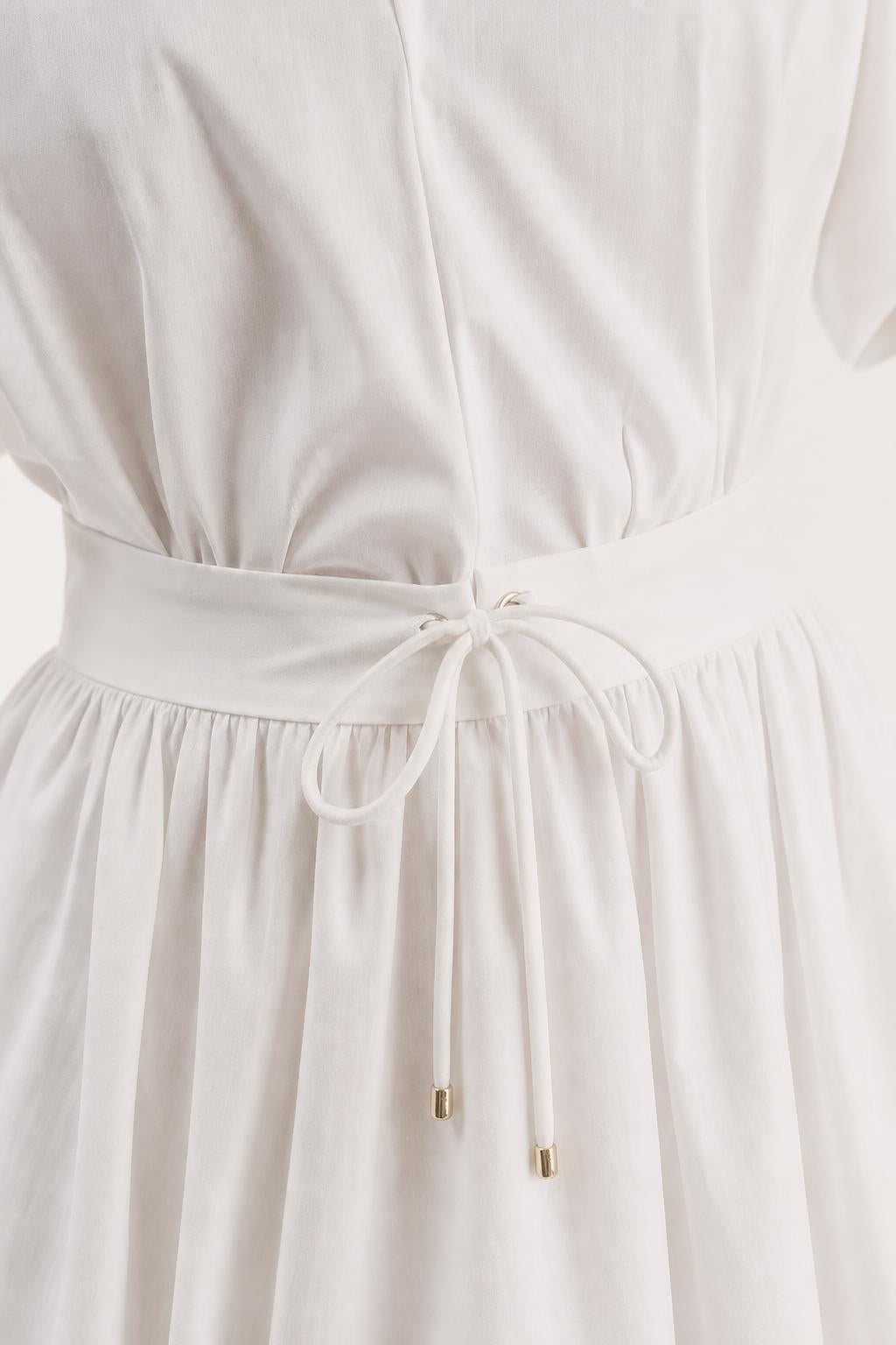 Close-up of drawstring waist detail on white mini dress