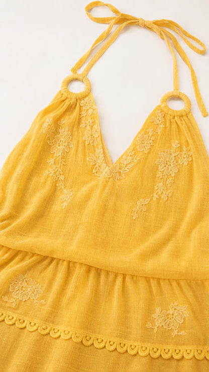 Close-up detail of yellow dress embroidery and halter neckline