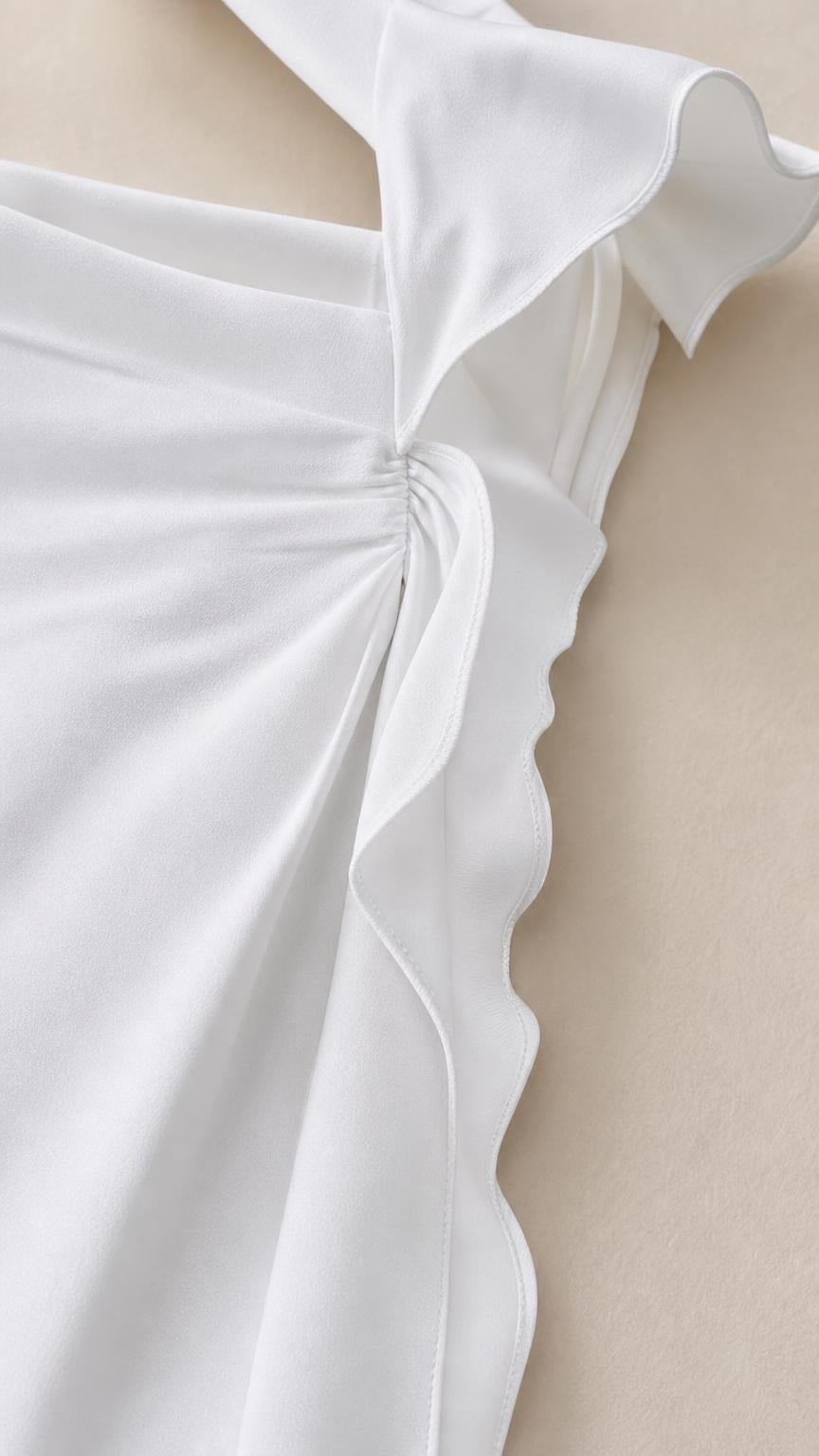 Close-up detail of shoulder strap and side ruffles on white dress