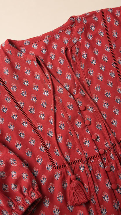 Close-up detail of V-neckline and button trim on red top