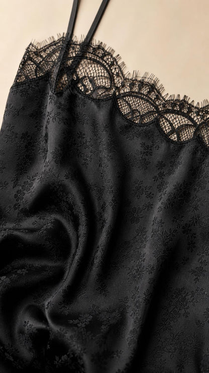 Close-up of black satin fabric with intricate lace trim and spaghetti straps