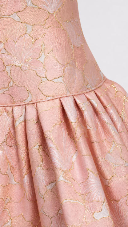 Close-up of pink floral jacquard fabric and pleated skirt detail
