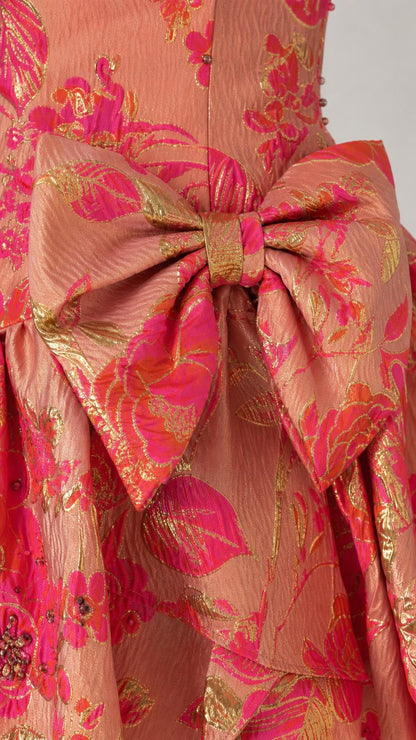 Close-up detail of oversized bow and metallic brocade fabric on dress