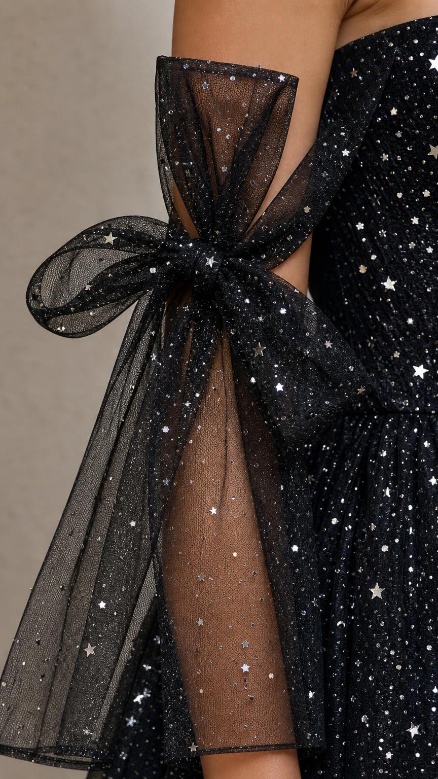 Close-up of sheer off-the-shoulder sleeve with tulle bow and star glitter print