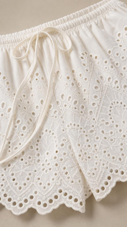 Close-up detail of the white eyelet shorts featuring drawstring and scalloped hem