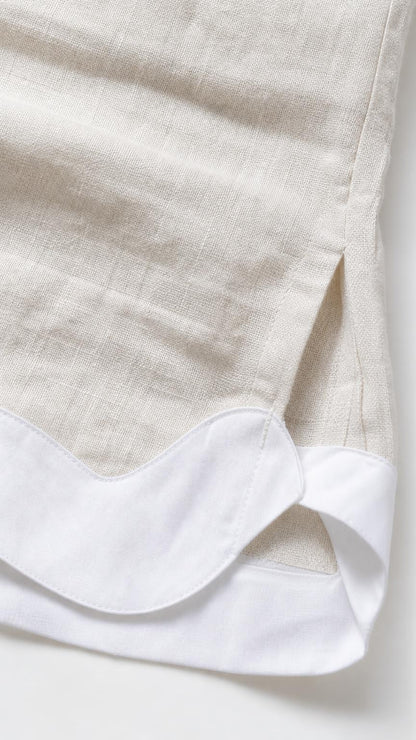 Close-up detail of white scalloped hem trim on beige fabric