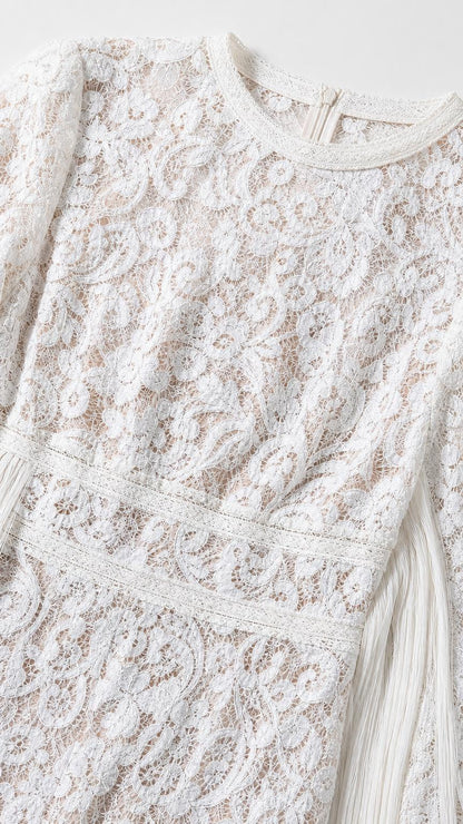 Close-up detail of lace pattern and round neckline on white jumpsuit