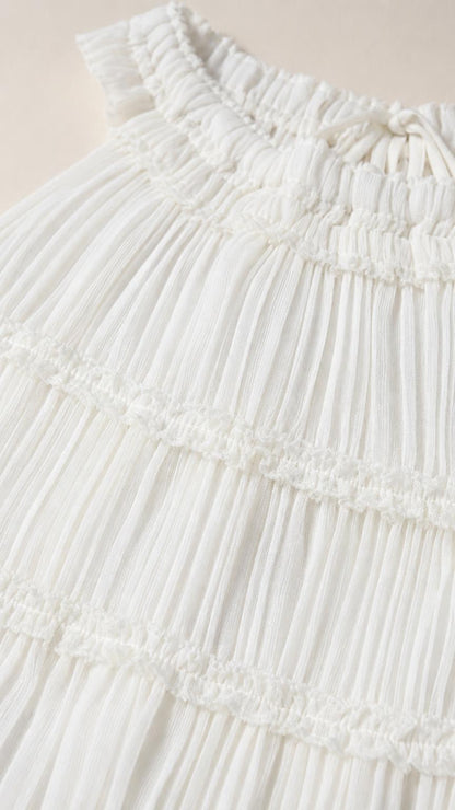 Close-up detail of pleated fabric and neckline on white top