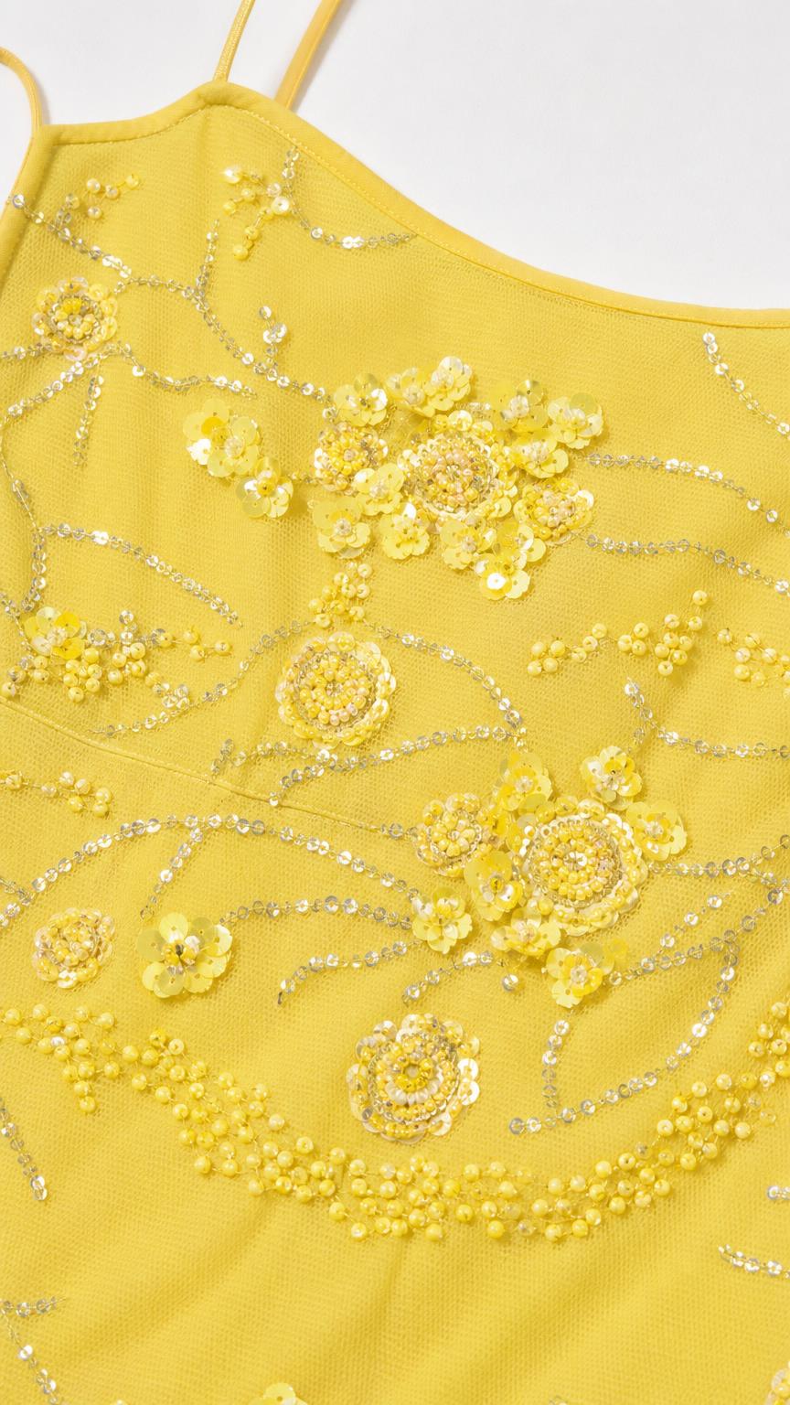 Close-up detail of yellow dress fabric with beads and sequins