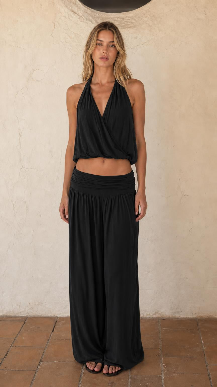 Woman wearing black halter crop top and wide leg pants set
