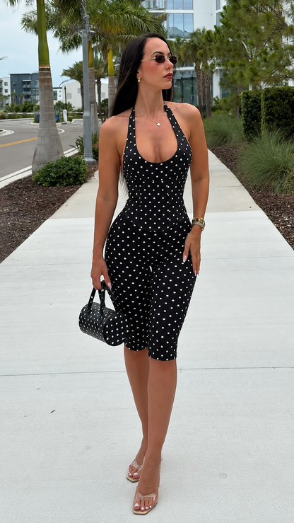 Front view of black polka dot halter biker jumpsuit with matching mini bag