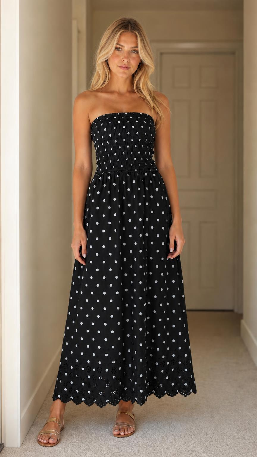 Front view of woman wearing black polka dot strapless maxi dress
