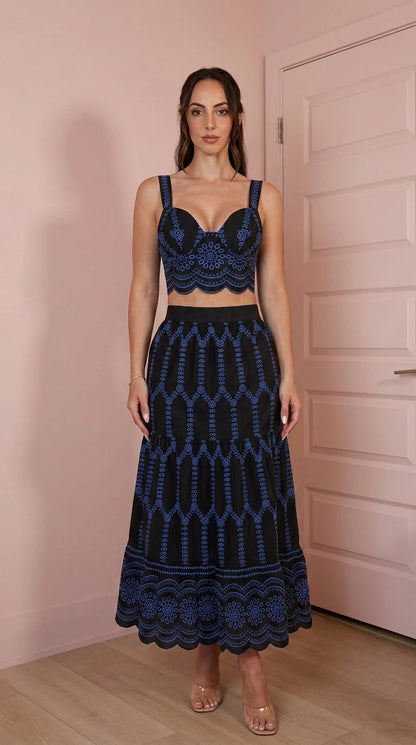 Model wearing black two-piece embroidered crop top and skirt set