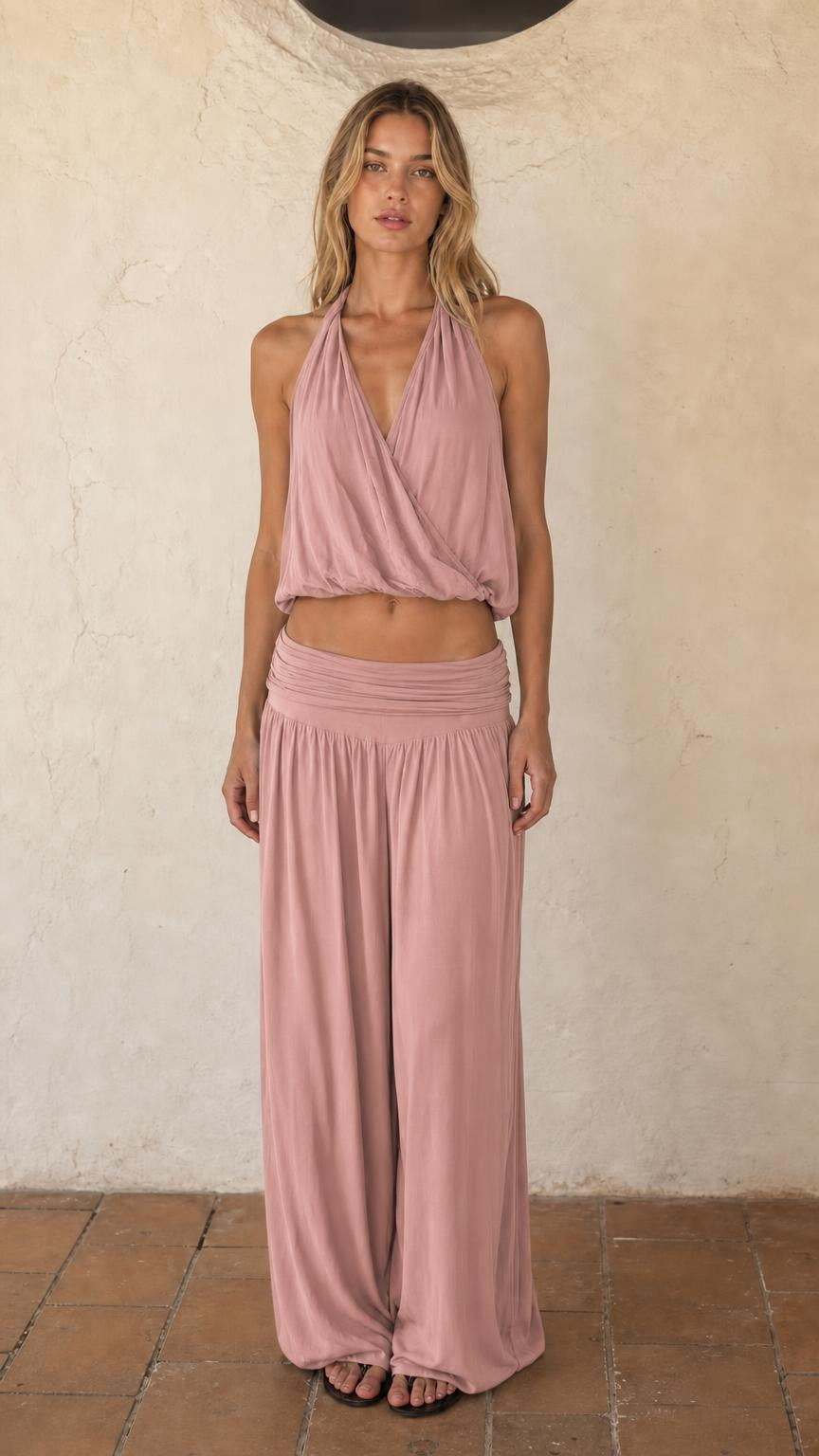 Woman wearing dusty pink halter crop top and wide leg pants set