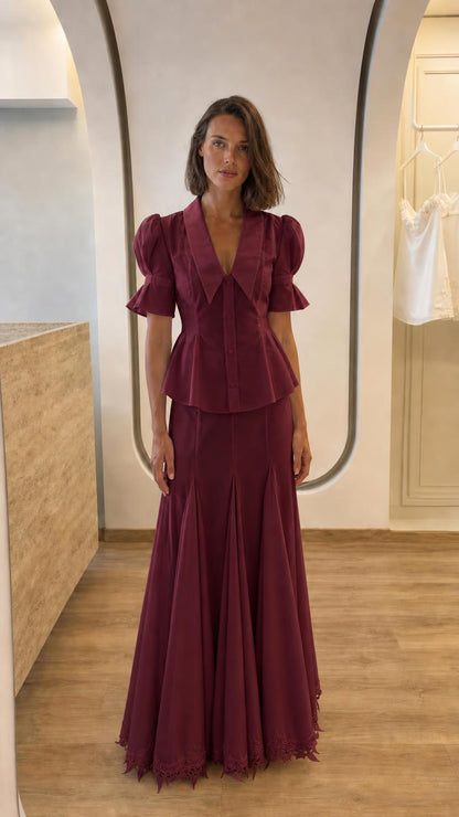 Front view of woman in burgundy two-piece peplum top and maxi skirt set