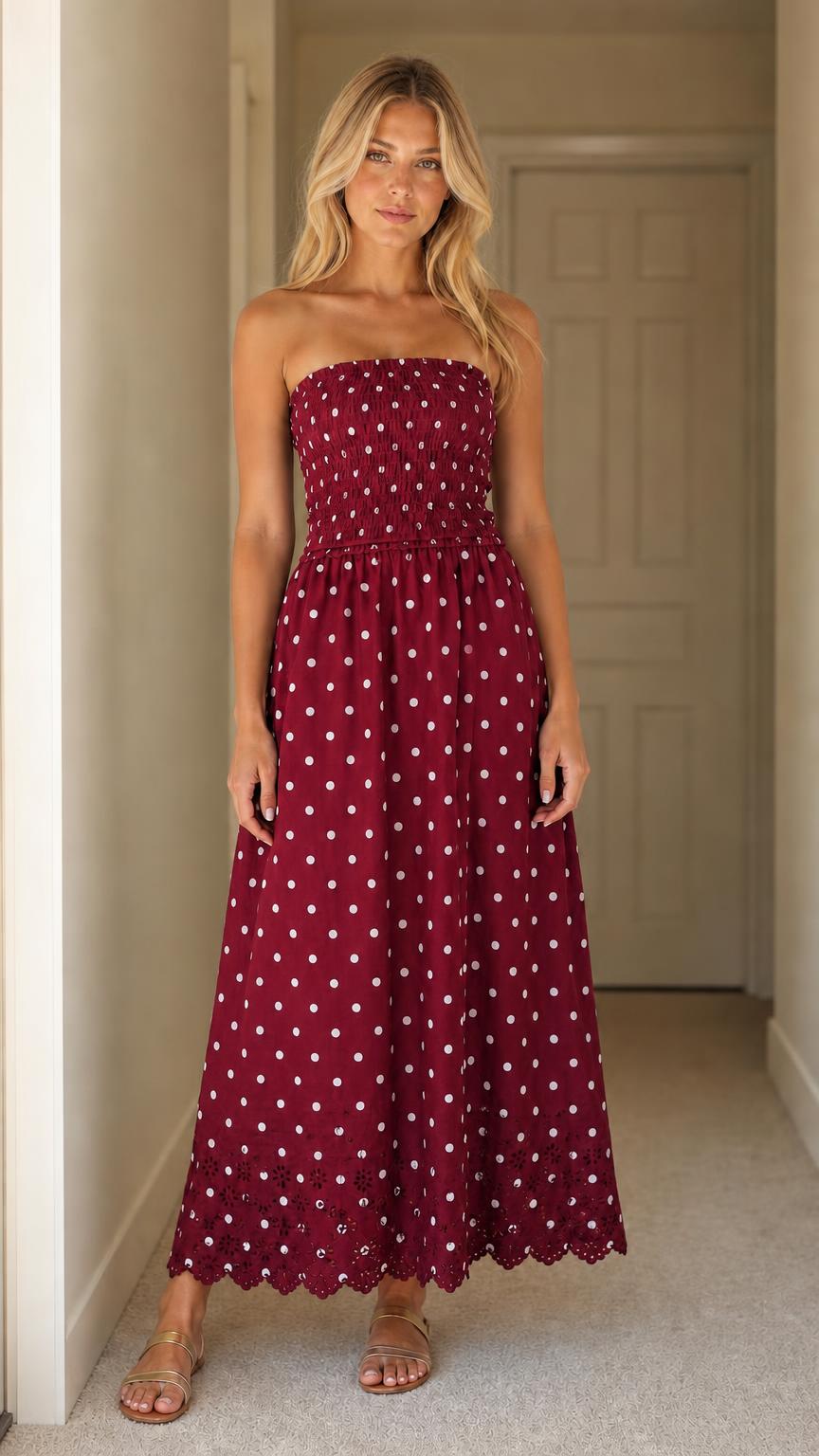 Front view of woman wearing burgundy polka dot strapless maxi dress