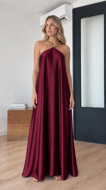 Model wearing burgundy satin halter maxi dress
