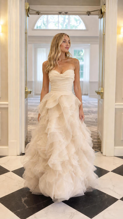 Model wearing champagne colored strapless tulle ball gown evening dress